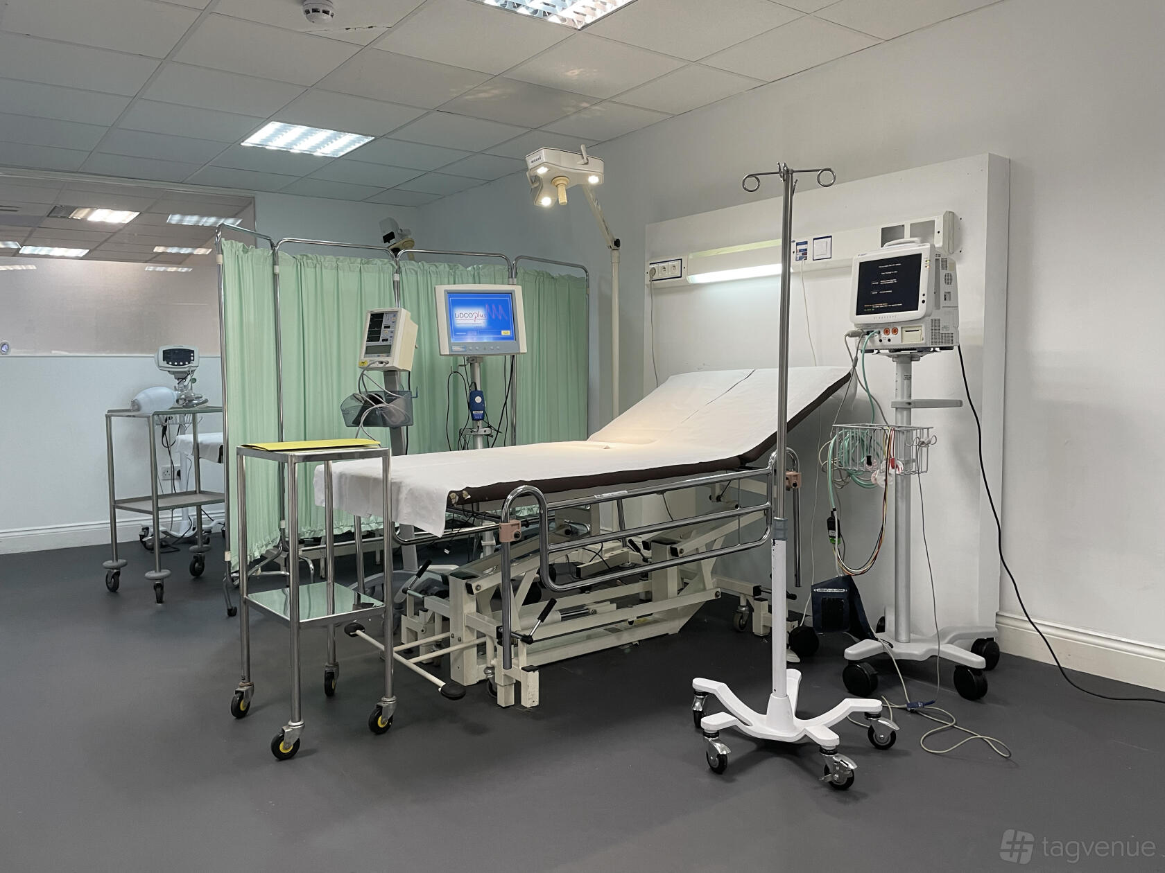 A photo studio with a hospital bed, privacy screen, medical monitors, and IV stand at Blackout studio & Medical Room.
