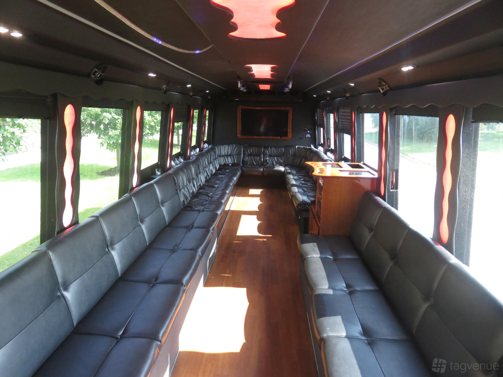 A party bus with wraparound black leather seating, hardwood floors, and accent lighting at Mermaid Luxury Limo Mississauga.