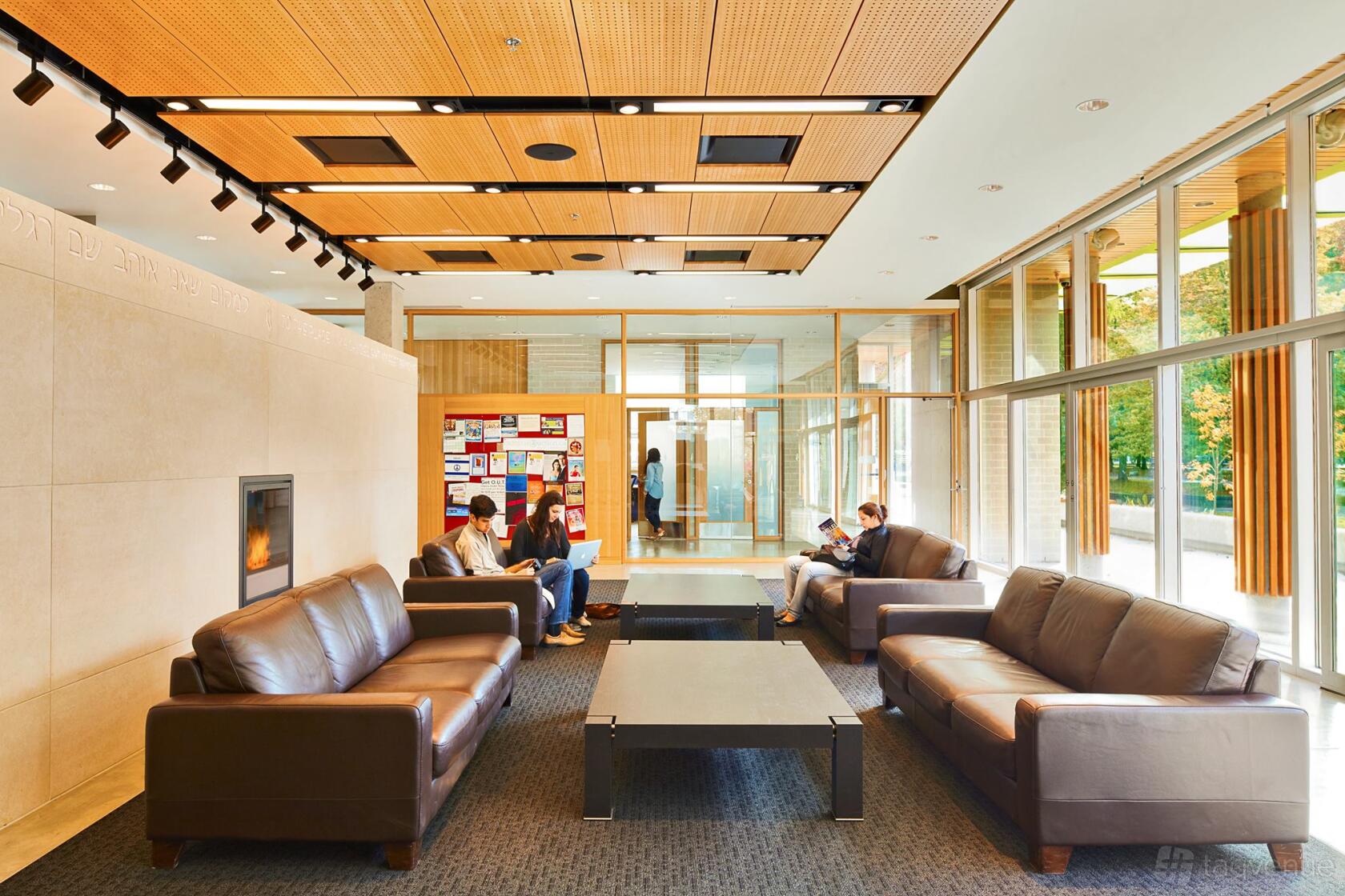 A lounge with leather sofas, a fireplace, and floor-to-ceiling windows at Hillel BC.