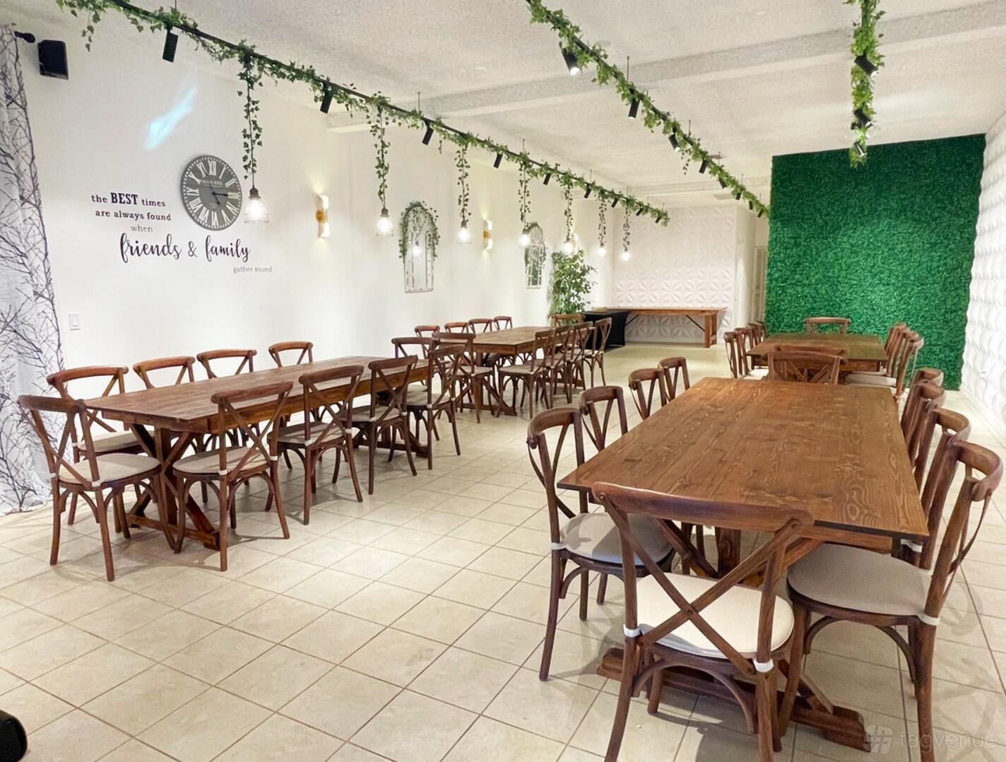 An event venue with wooden tables and chairs, tile floors, and greenery garlands hanging from the ceiling at Atheena Studio.