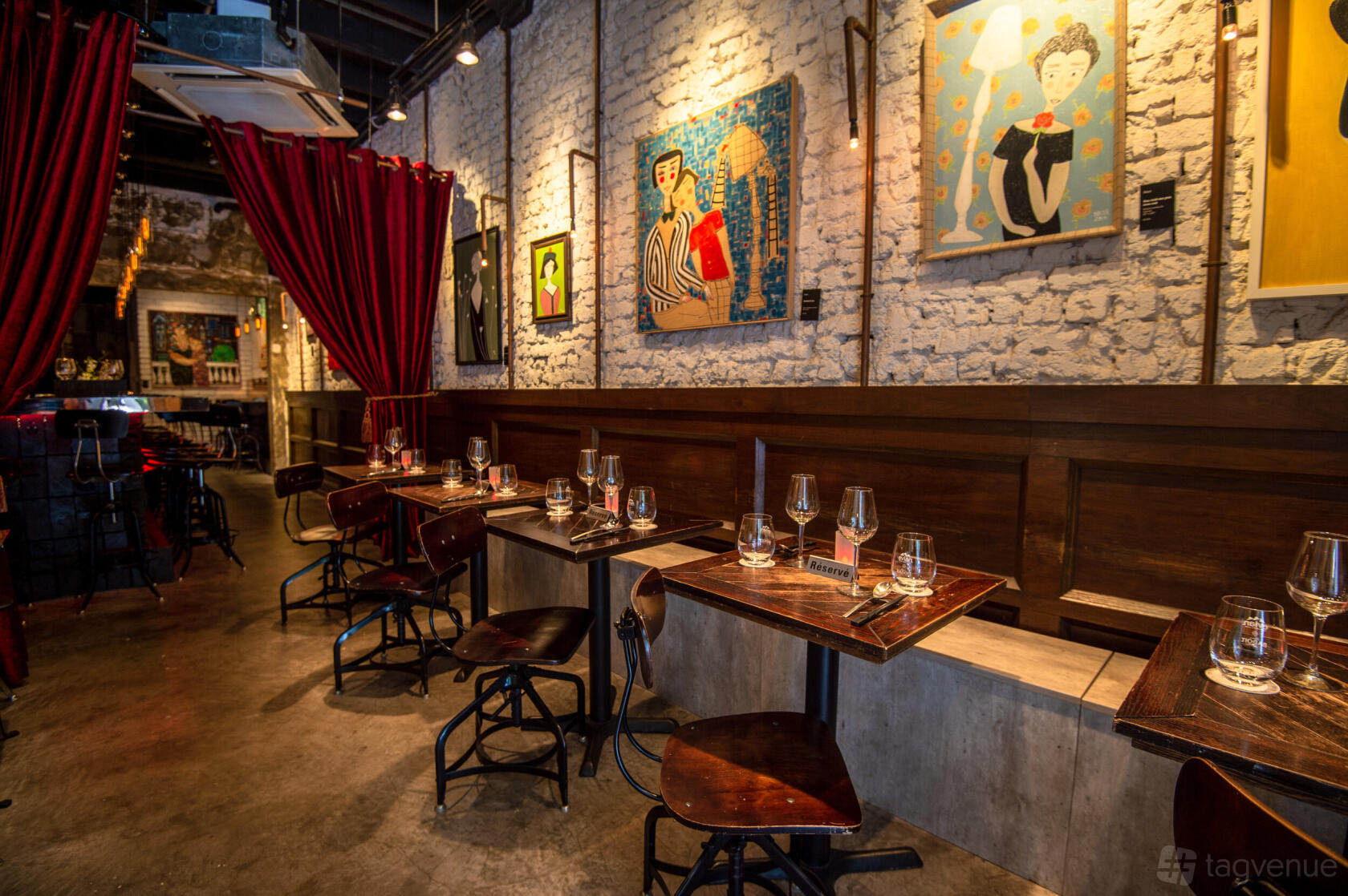 A restaurant with exposed brick walls, red velvet curtains, and modern art at Maison Ikkoku