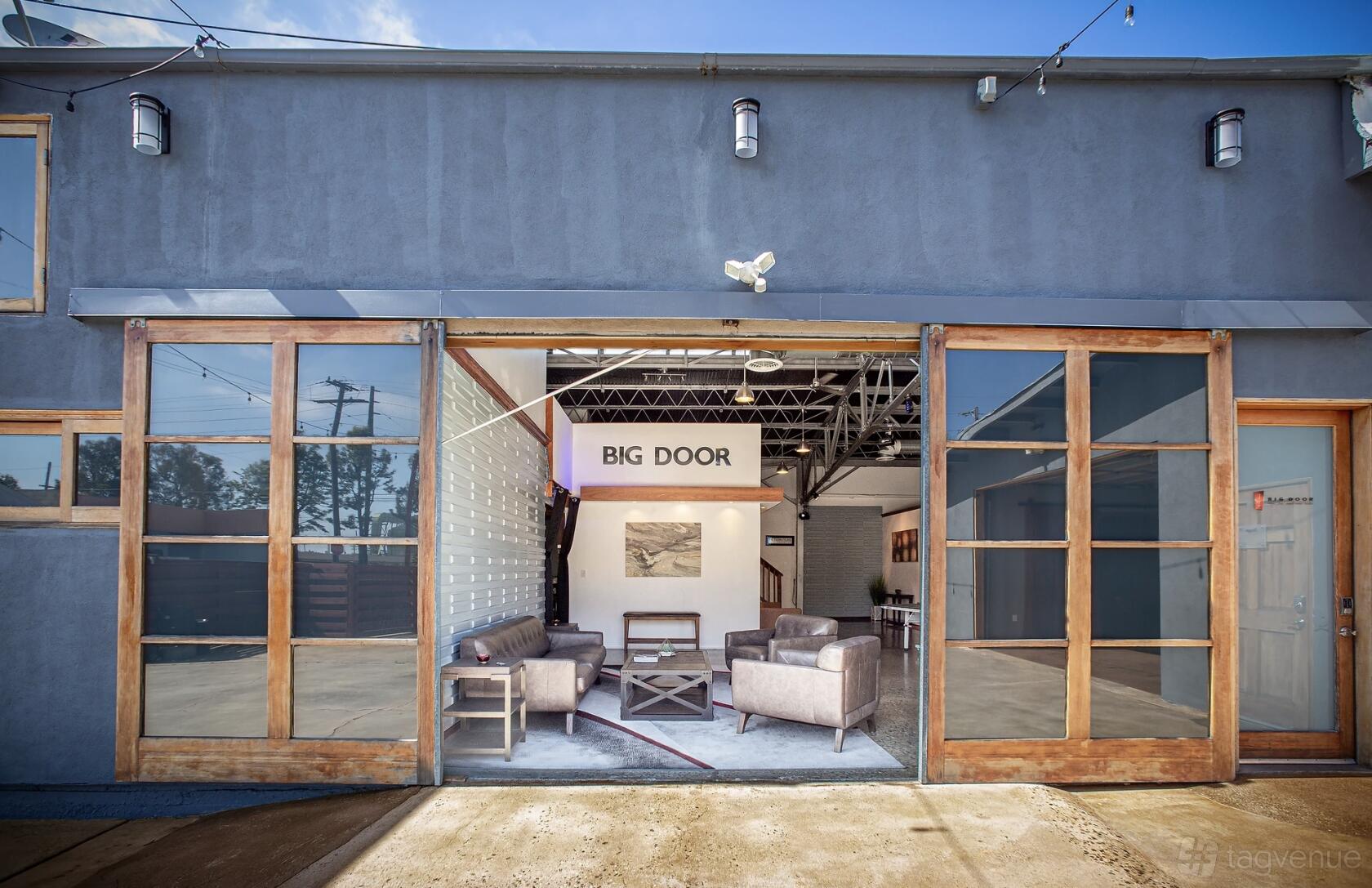 An event venue with glass garage doors, exposed beams, and lounge seating at Big Door Studios.