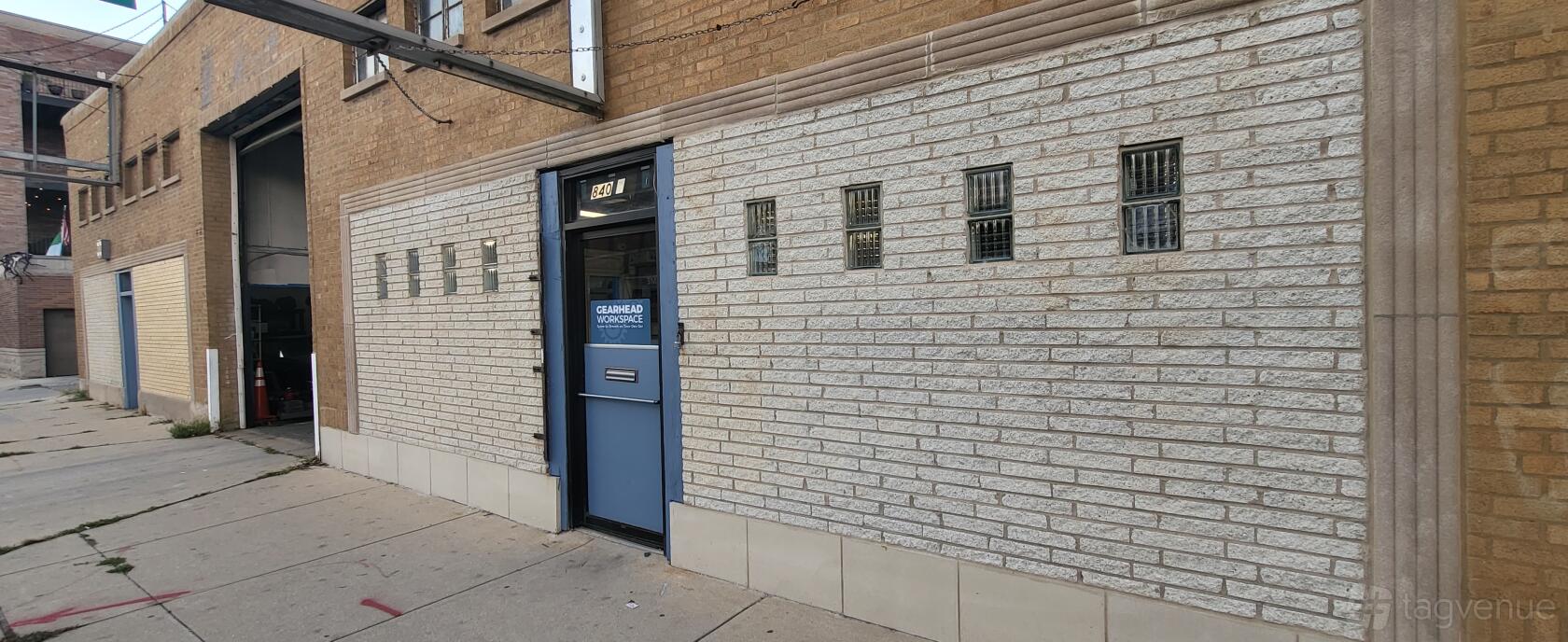 A warehouse entrance with a blue door and glass block windows at Gearhead Workspace.