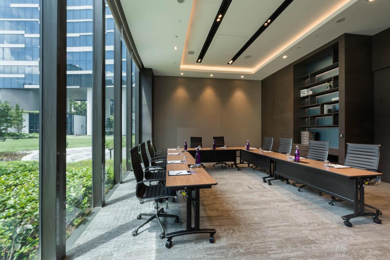A meeting room with floor-to-ceiling windows, modern chairs, and built-in shelving at Novotel Singapore on Stevens.