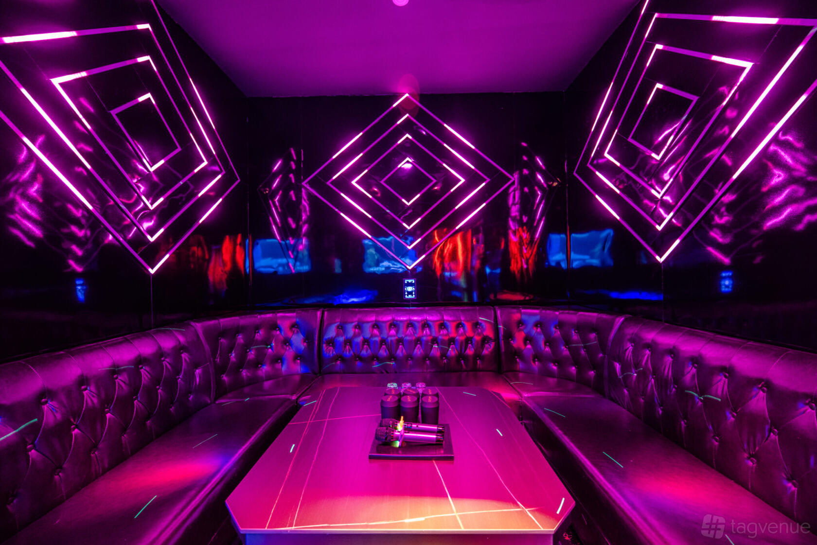 A karaoke function room with tufted black leather seating, neon geometric wall lights, and a central table at G-Funk KTV.
