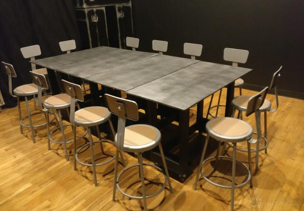 A gallery meeting room with a large rectangular table and metal chairs on a wooden floor at The Time Gallery.