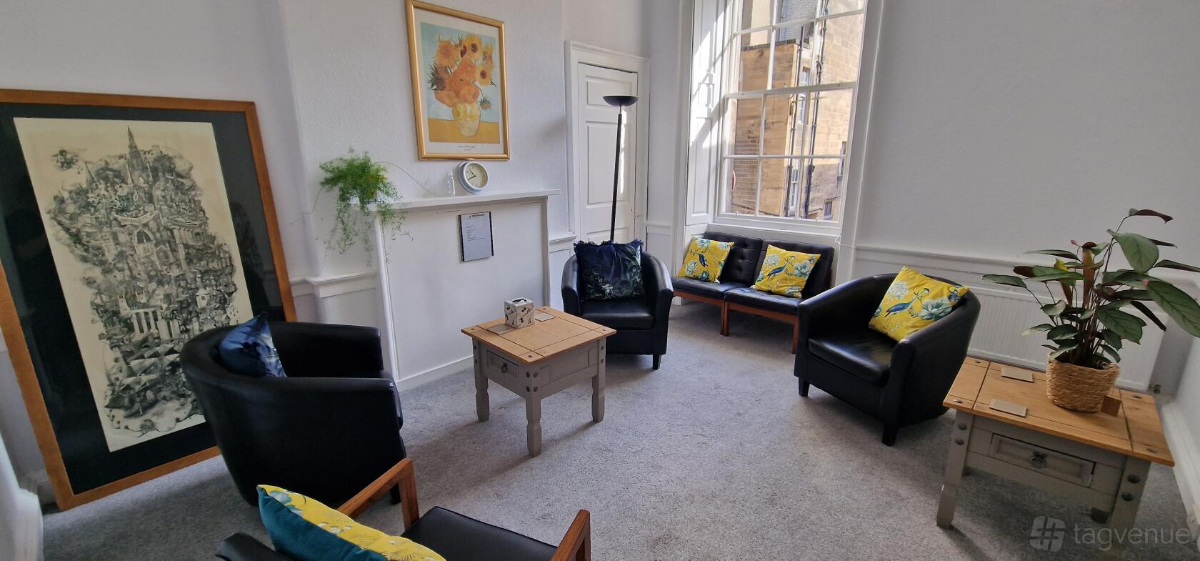 A meeting room with black armchairs, a wooden coffee table, floral cushions, and large window at Birthlink.