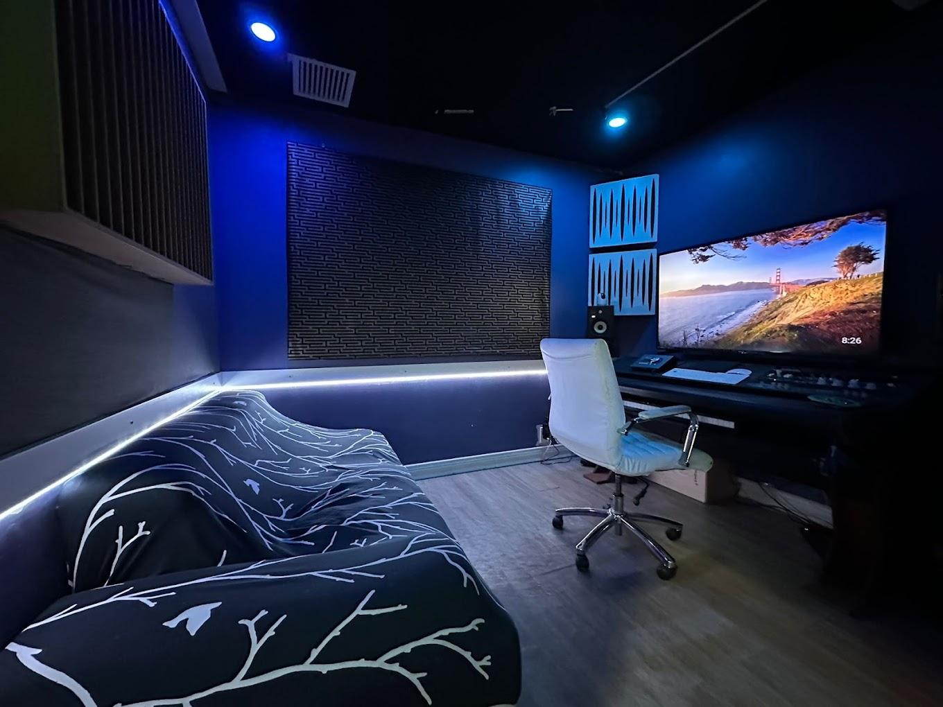 A recording studio with LED accent lighting, soundproof panels, a mixing desk, and a large screen at World Famous Sound Studios.