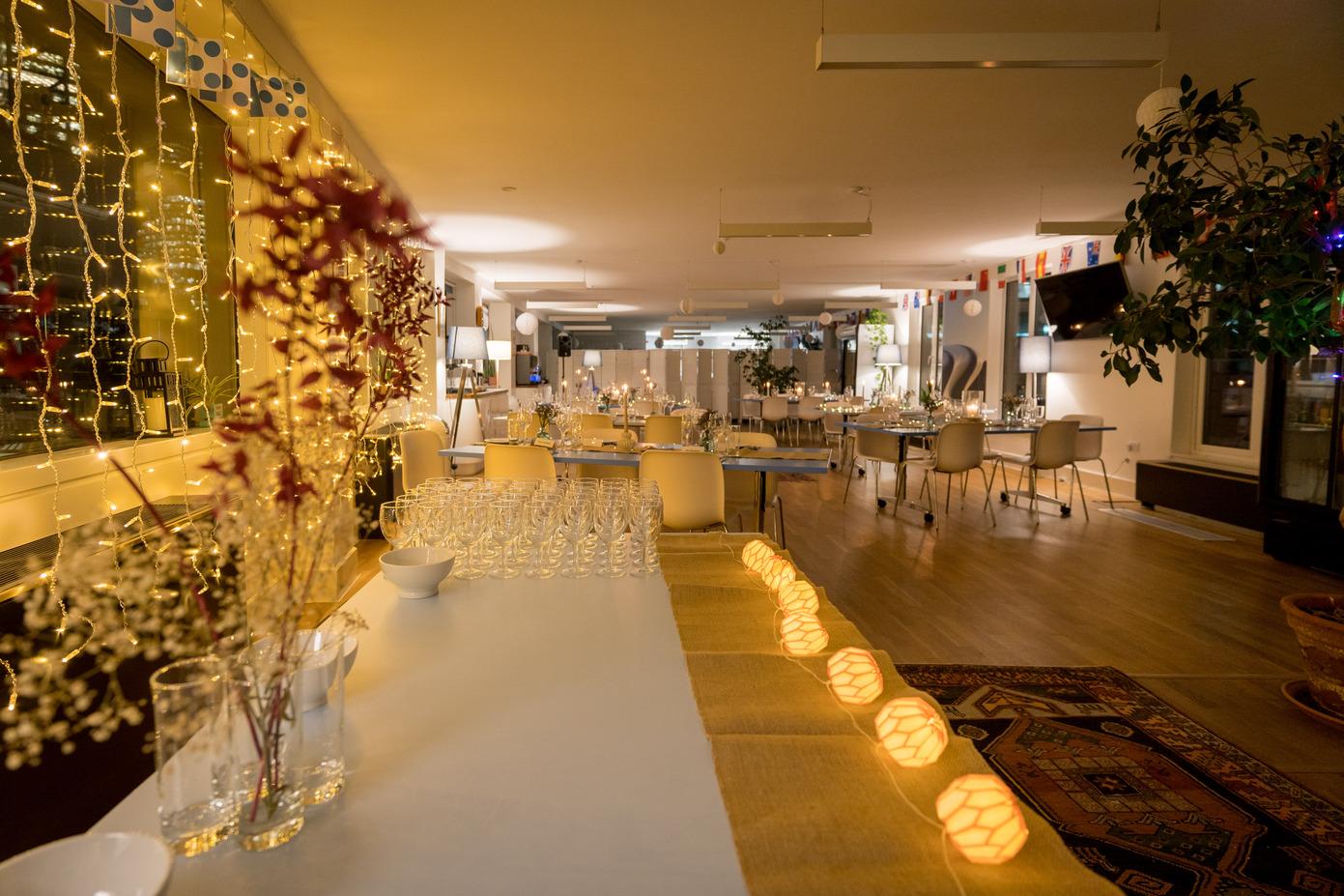 An event space with hanging string lights, round tables, and glassware displays at Wallacespace Spitalfields.