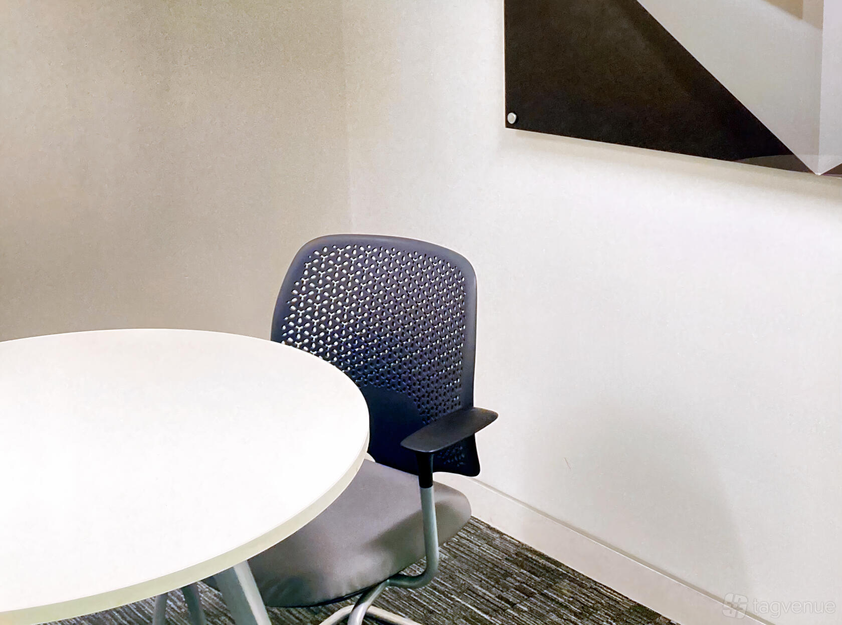 A meeting room with a white round table, ergonomic chair, and neutral walls at Rivvia Pronto Meeting Rooms.