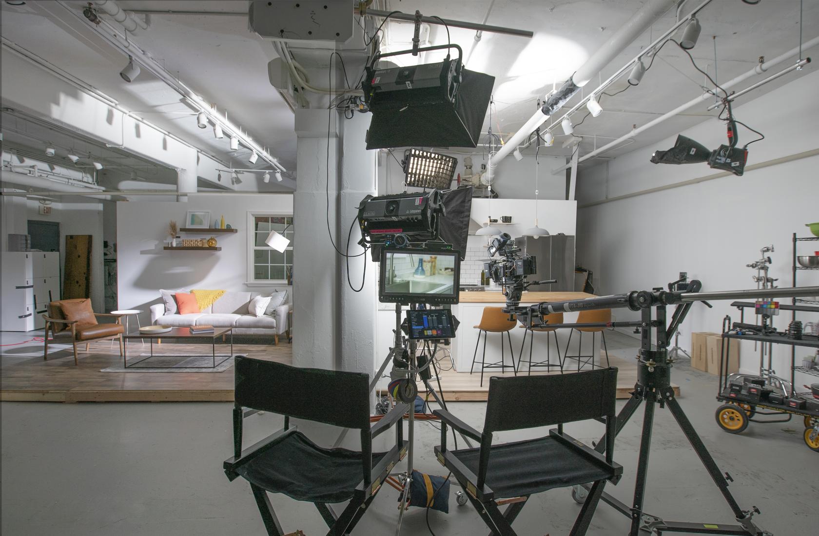 A film studio with professional lighting, camera equipment, and a living room set at Recreation Studios.