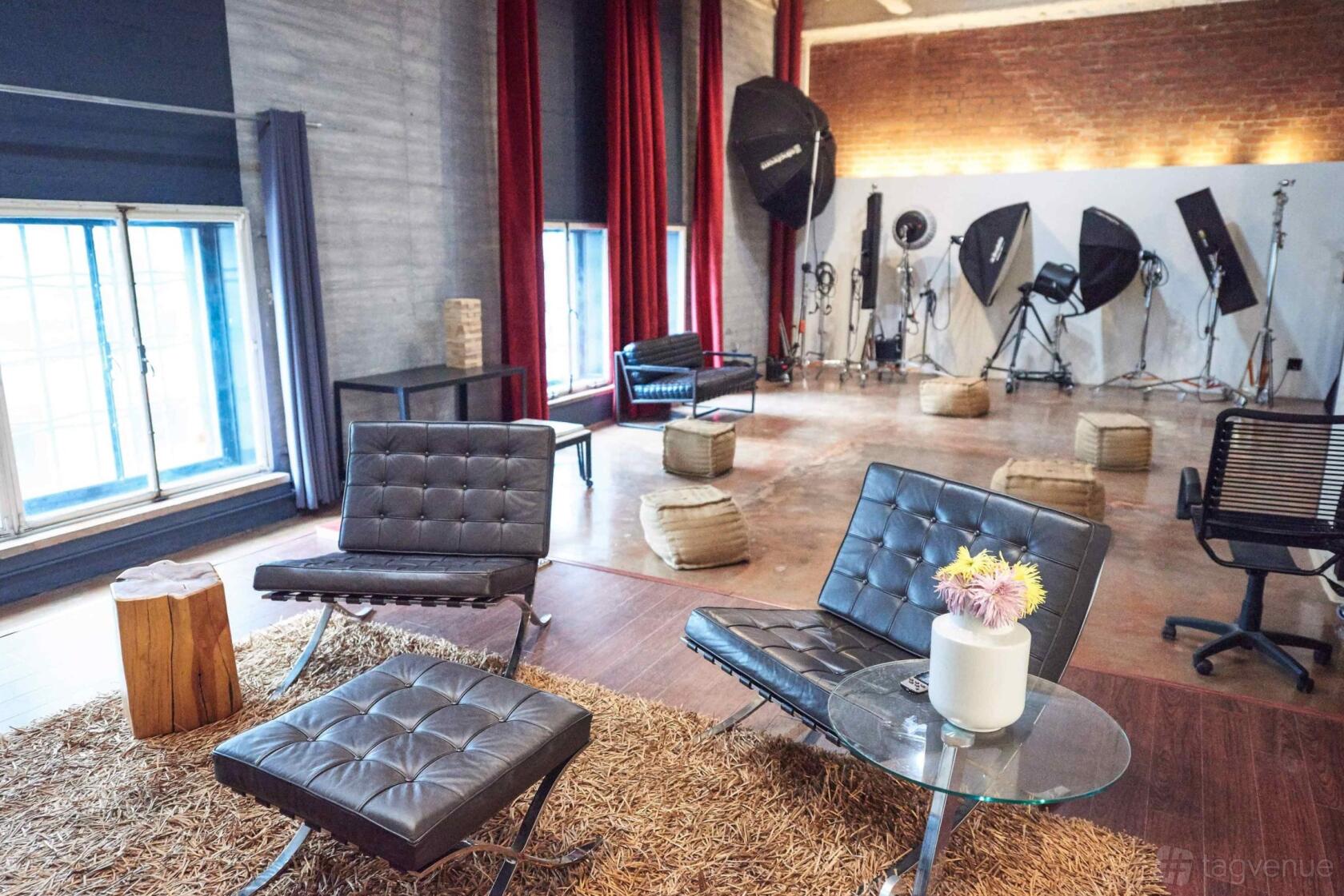 A photo studio with large windows, red curtains, leather chairs, and professional lighting equipment at JUDE STUDIO LOS ANGELES.