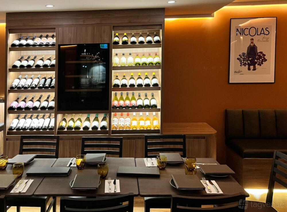 An event space in a restaurant with a wall-mounted wine display, wooden shelving, and a long dining table at Hannah's Beecroft.