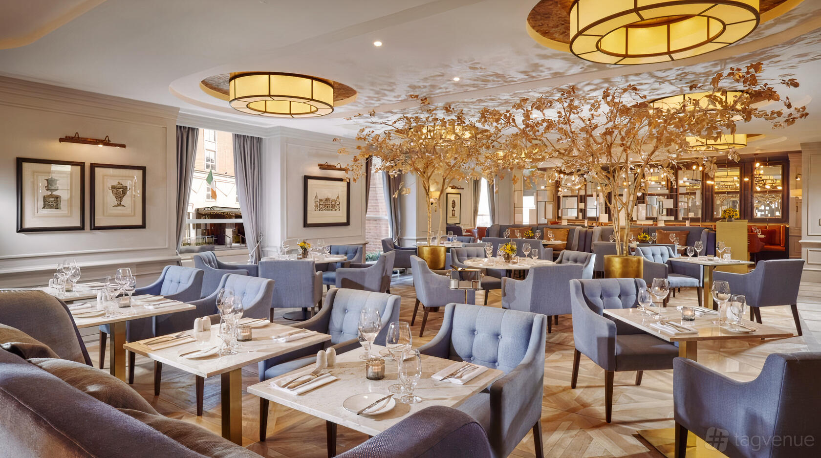 A hotel restaurant with blue velvet chairs, marble tables, and decorative tree centerpieces at The Davenport Hotel.