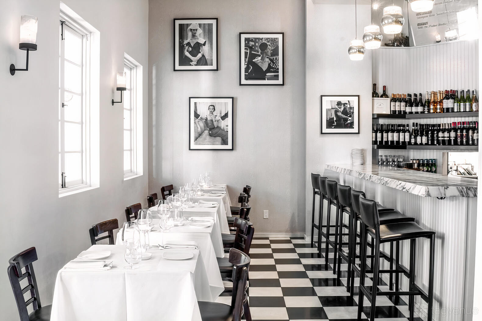 A restaurant with black and white checkered floors, marble-topped bar, and framed photos on white walls at Mora Italiano Encino.