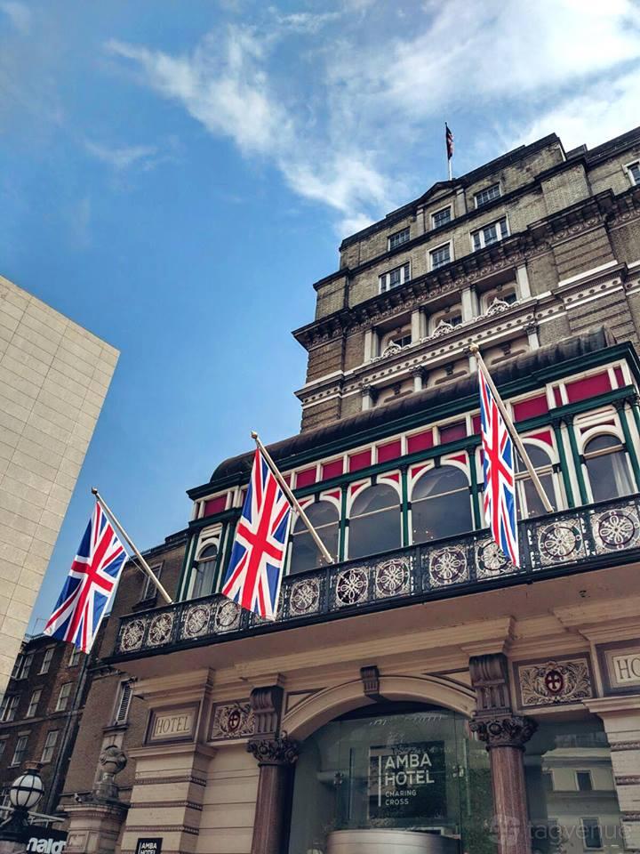 A hotel exterior with arched windows, wrought iron balcony, and Union Jack flags at Clermont Charing Cross.
