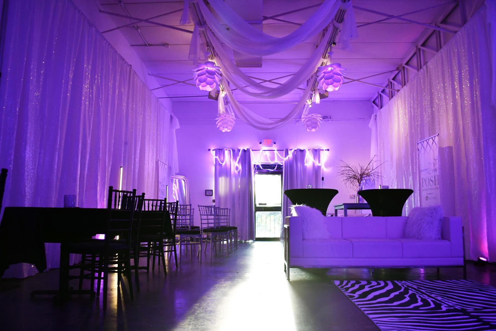 An event venue with sheer white drapes, purple accent lighting, and hanging fabric decorations at Perimeter Zen.