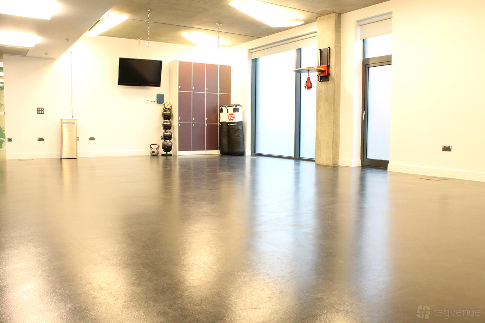 An event venue with a spacious studio, fitness equipment, and floor-to-ceiling windows at Osmani Centre.