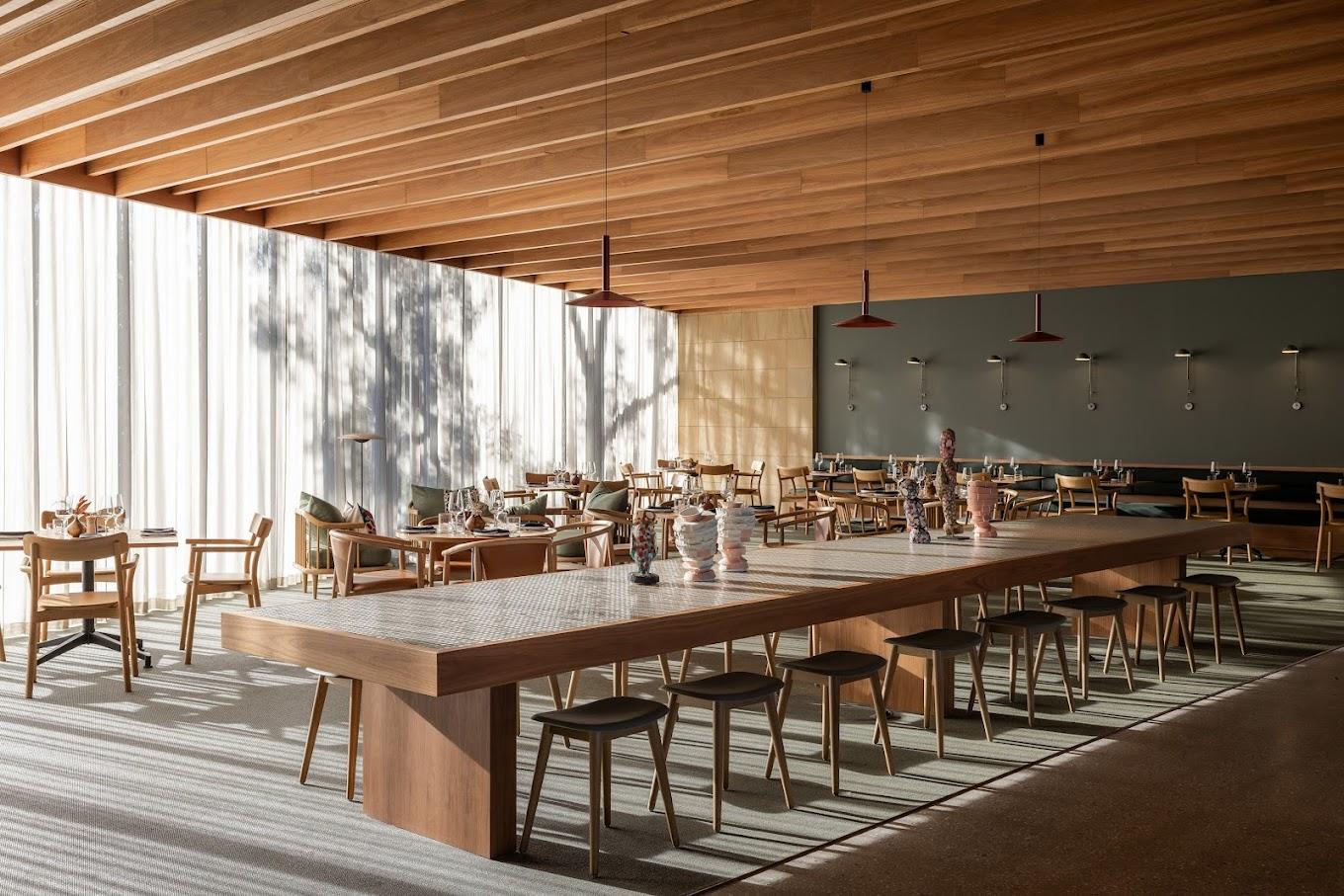A restaurant with floor-to-ceiling sheer curtains, wooden slat ceiling, and light wood furniture at Wonil Hotel Perth - Handwritten Collection.