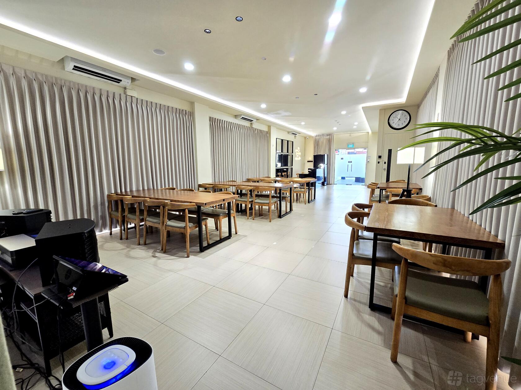 An event venue with wood tables, matching chairs, tiled floors, and large windows with beige curtains at HIGHfive Double Storey.