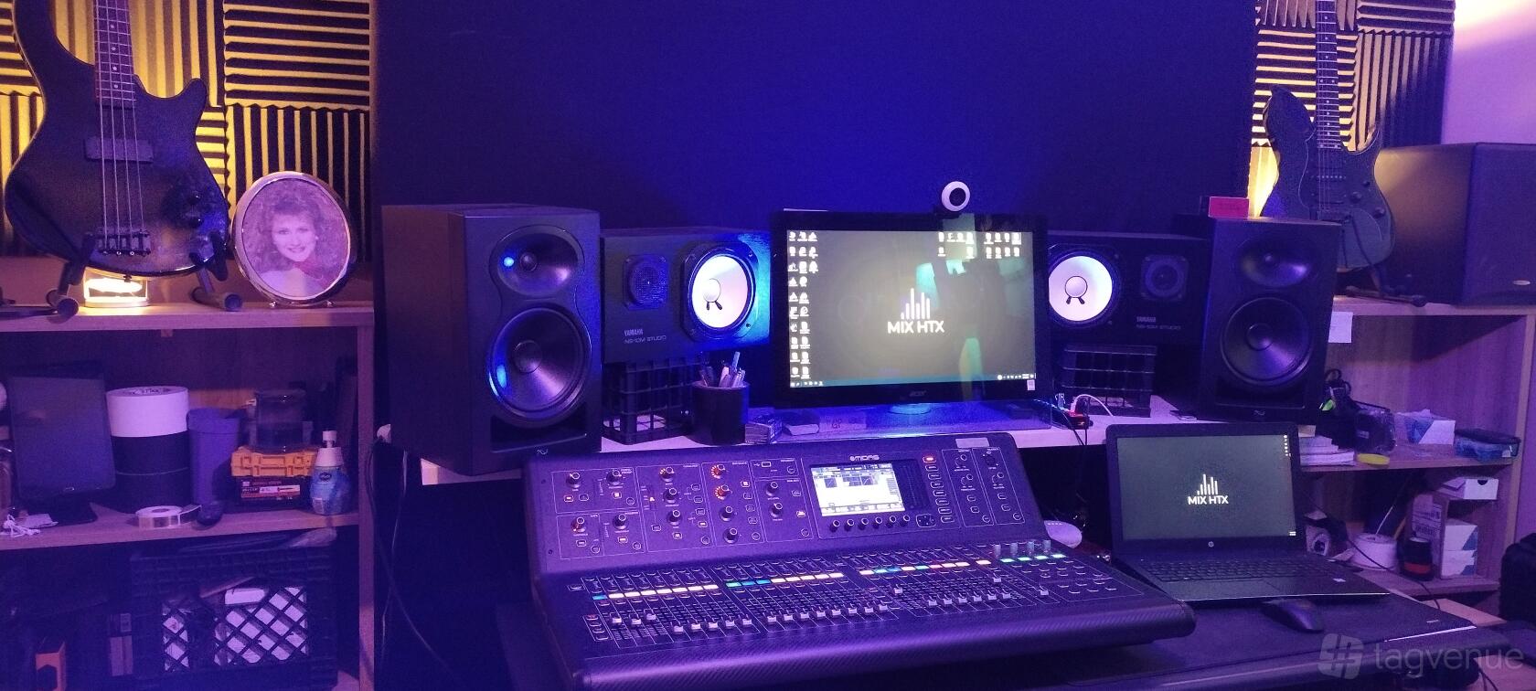 A recording studio with a digital mixing console, studio monitors, and dual screens at MIX HTX.