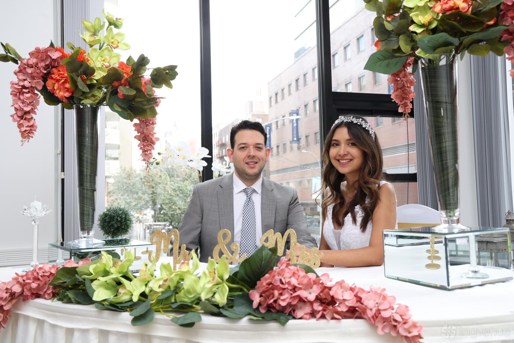 A loft with floor-to-ceiling windows, pink hydrangeas, and a white floral reception table at Hidden City.