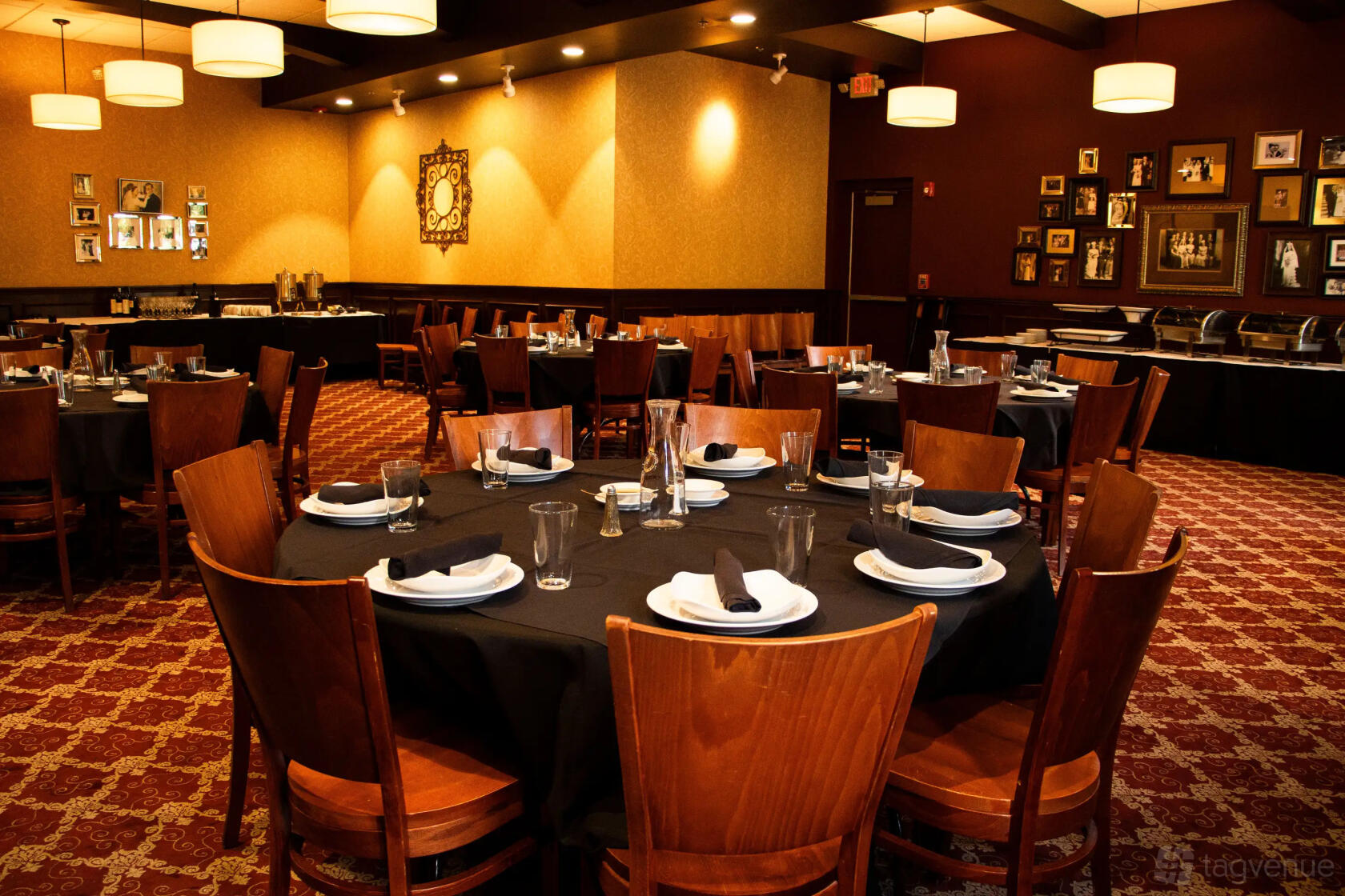 A dining room with round tables covered in black linens, wood chairs, and framed photos on the walls at Clara's Restaurant.