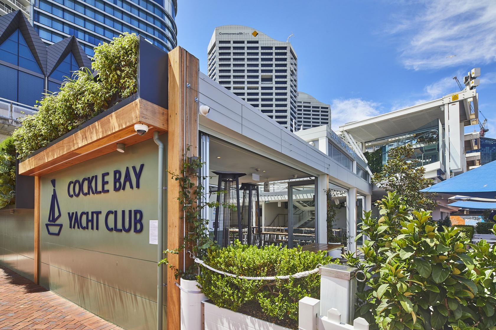 An event space with outdoor seating, greenery, and marina views at Cockle Bay Yacht Club.