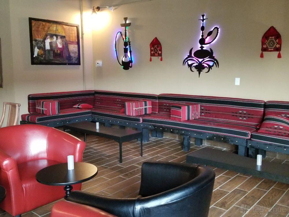 A hookah lounge with patterned banquette seating, wall art, and hookah decor at Alamodak Restaurant and Hookah bar.