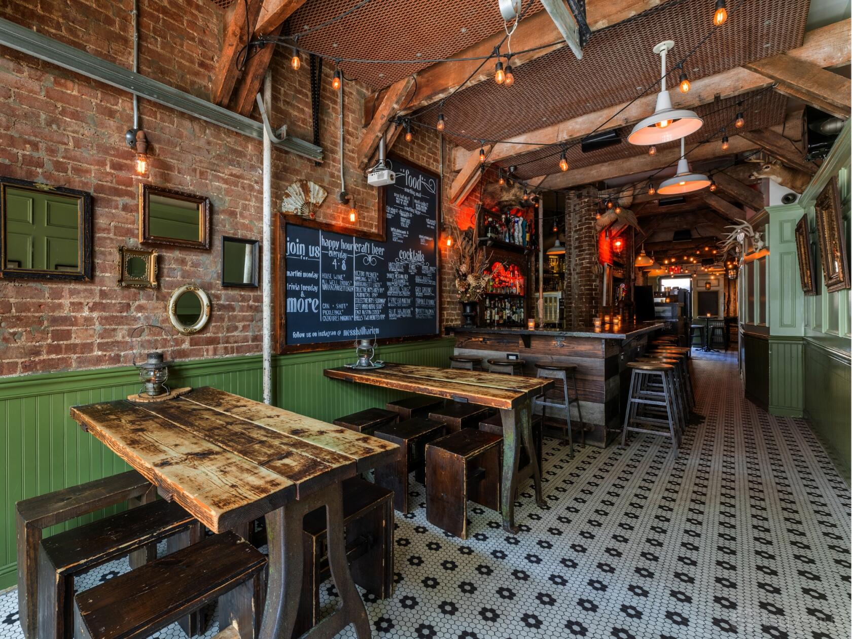 A bar with exposed brick walls, rustic wooden tables, chalkboard menus, and pendant lighting at Mess Hall.