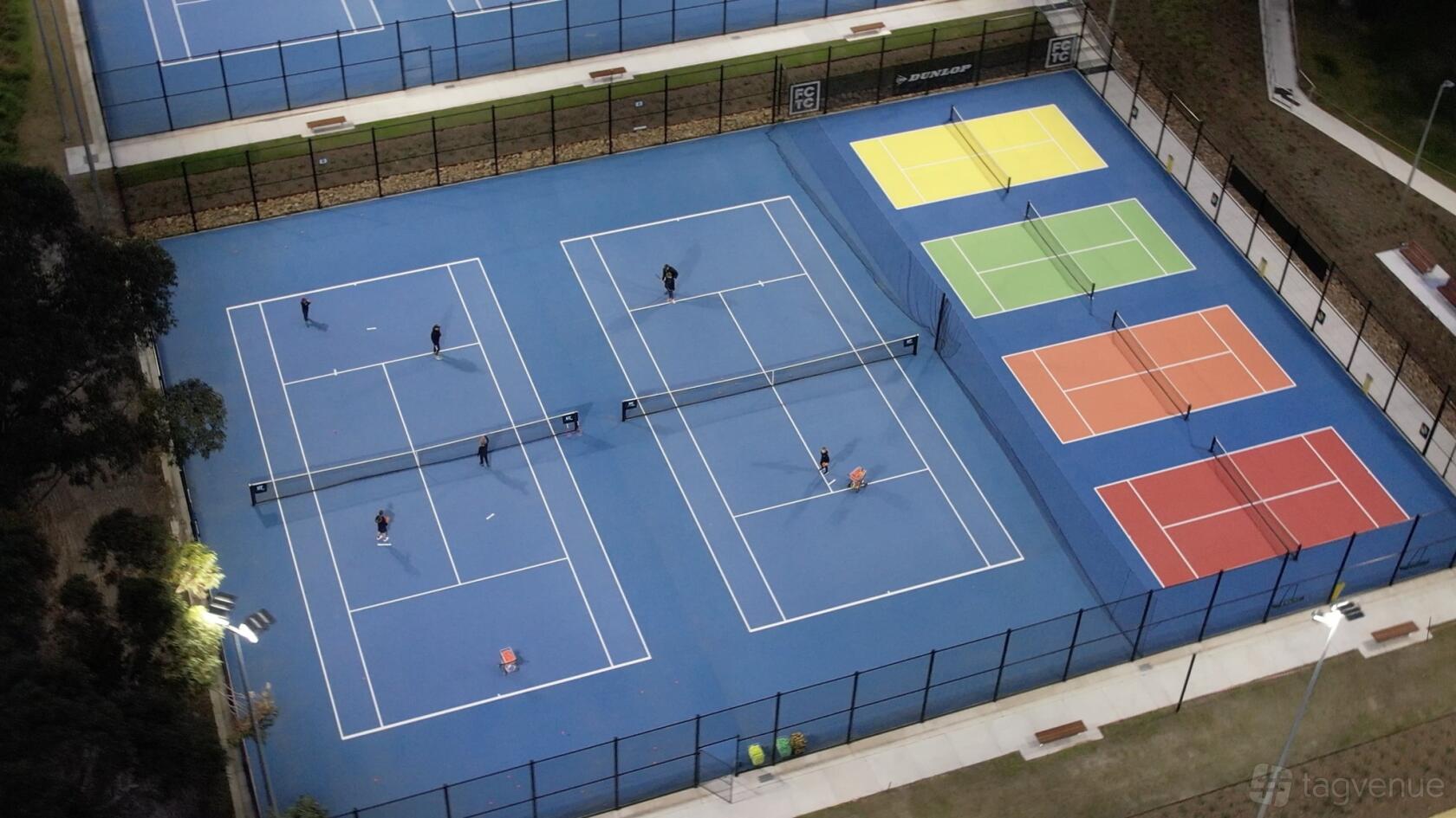 An event venue with multiple tennis courts, including blue and multi-colored courts at Frankston Centenary Tennis Club.