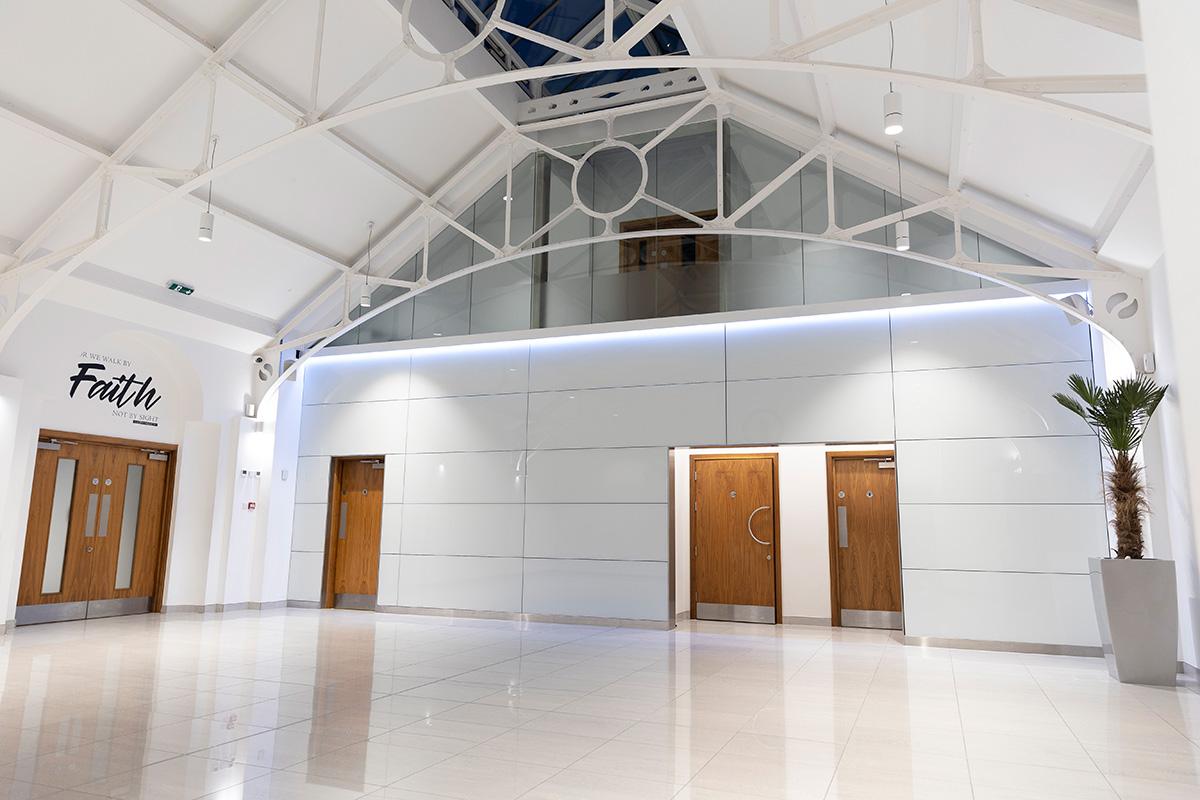 An event space with high vaulted ceilings, white walls, and polished tile floors at The Tab Centre.