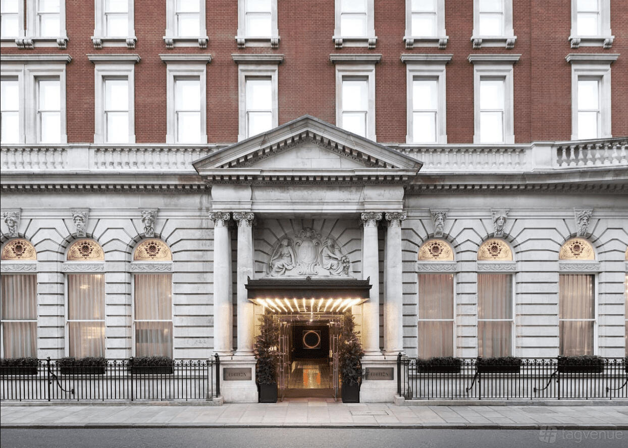 A hotel with a grand neoclassical façade, white columns, ornate stonework, and large windows at London EDITION.