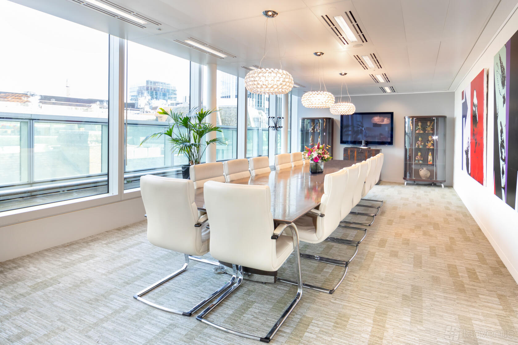 A boardroom with a long wooden table, white leather chairs, pendant lights, and floor-to-ceiling windows at Landmark: Old Broad Street, London.