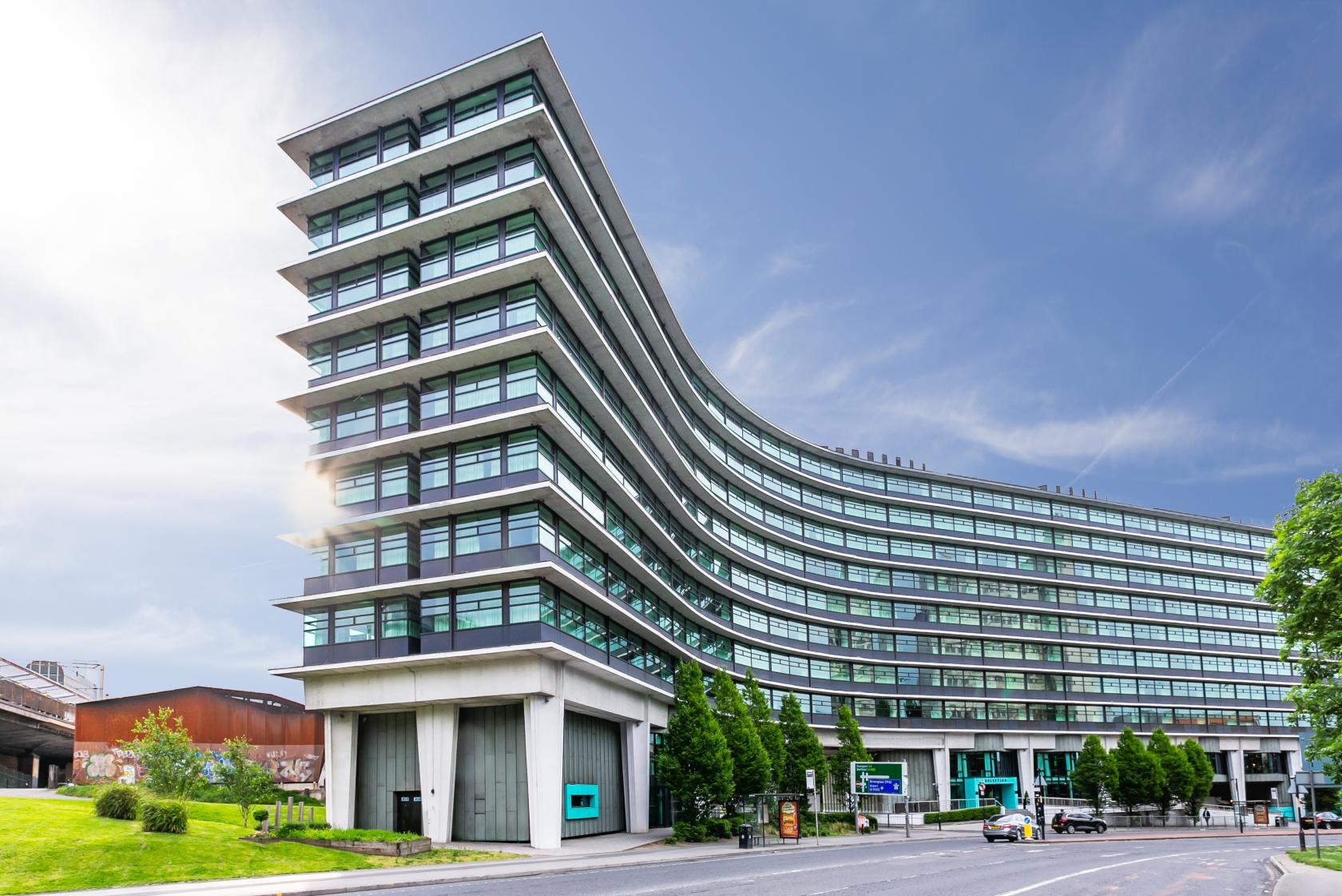 A hotel with a curved modern glass facade and multiple stories at Manchester Marriott Hotel Piccadilly.