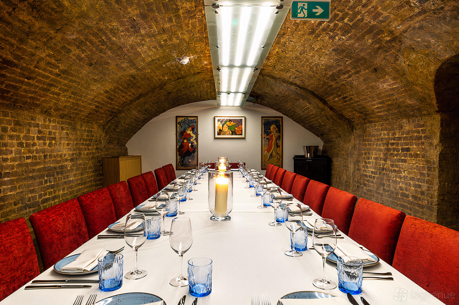 A brick-vaulted cellar bar with a long table, red cushioned chairs, and candlelit centerpiece at Bar 1790 at The Sandeman Quarter ltd.