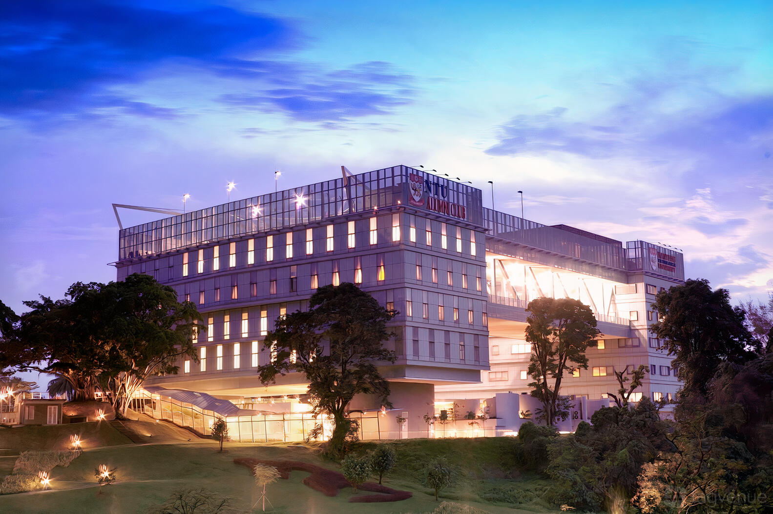 A meeting centre with large windows, illuminated exterior, and landscaped greenery at NTU Alumni Club Chill@5.