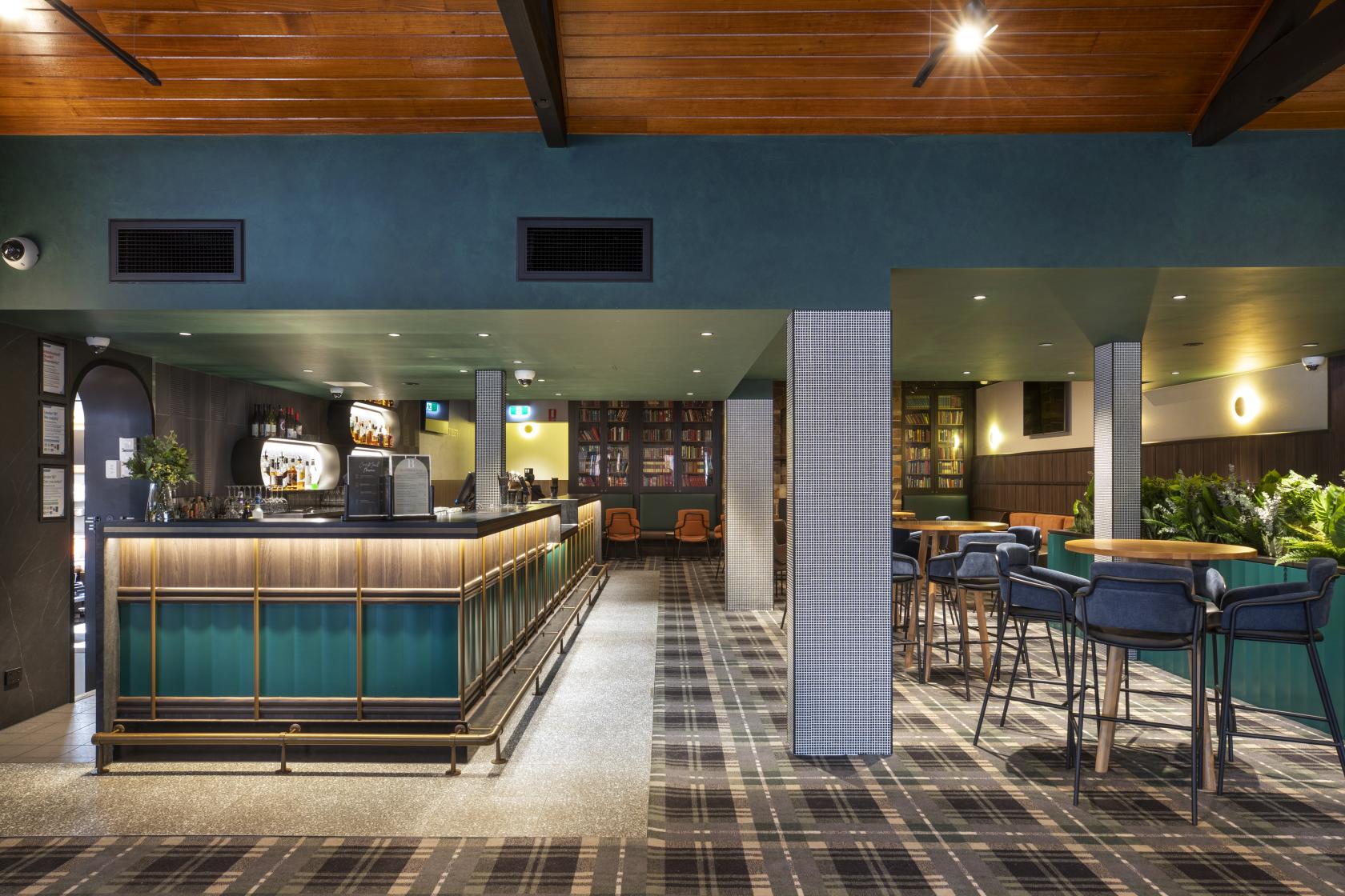 A pub with a plaid carpet, wood-paneled ceiling, central bar, and tall seating at Berwick Inn Hotel.
