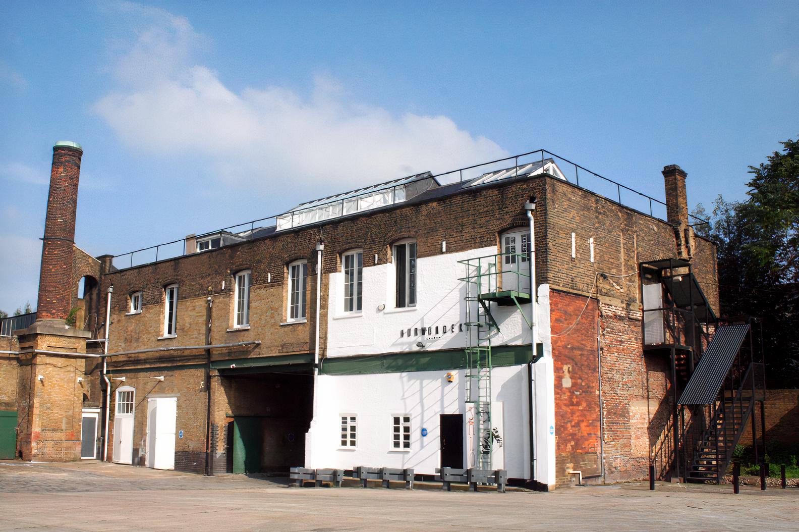 A film and photo studio with exposed brick exterior, metal staircase, and rooftop railing at Espero Studio.