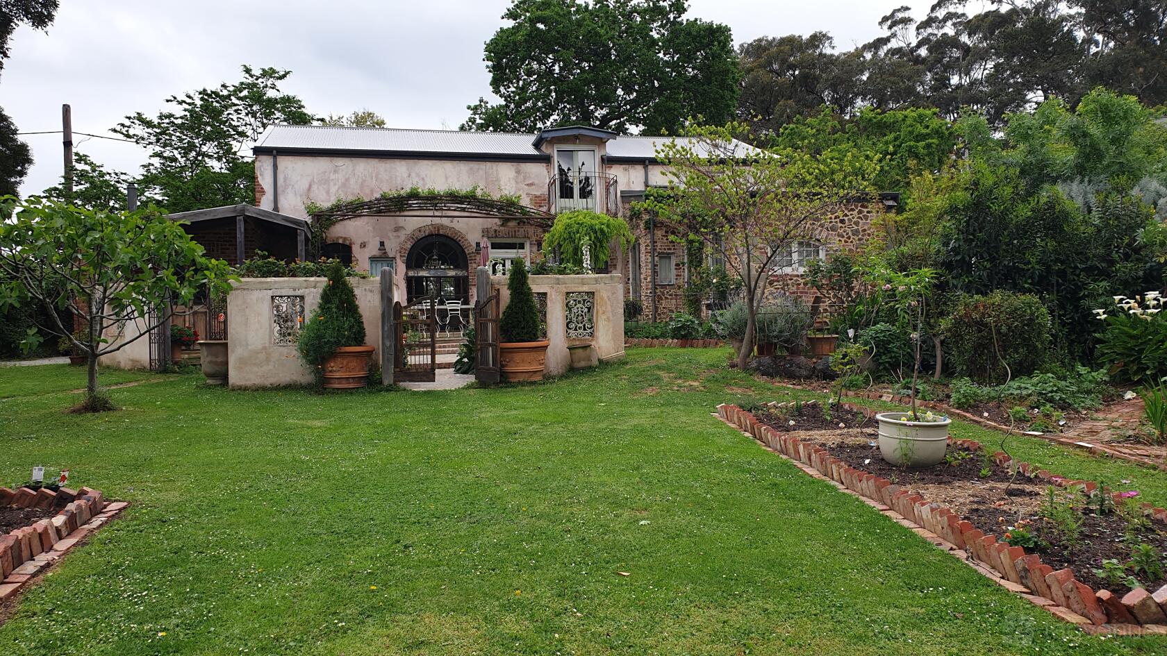 A country house with stone walls, arched doorway, vine-covered facade, and landscaped gardens at The Potterage.