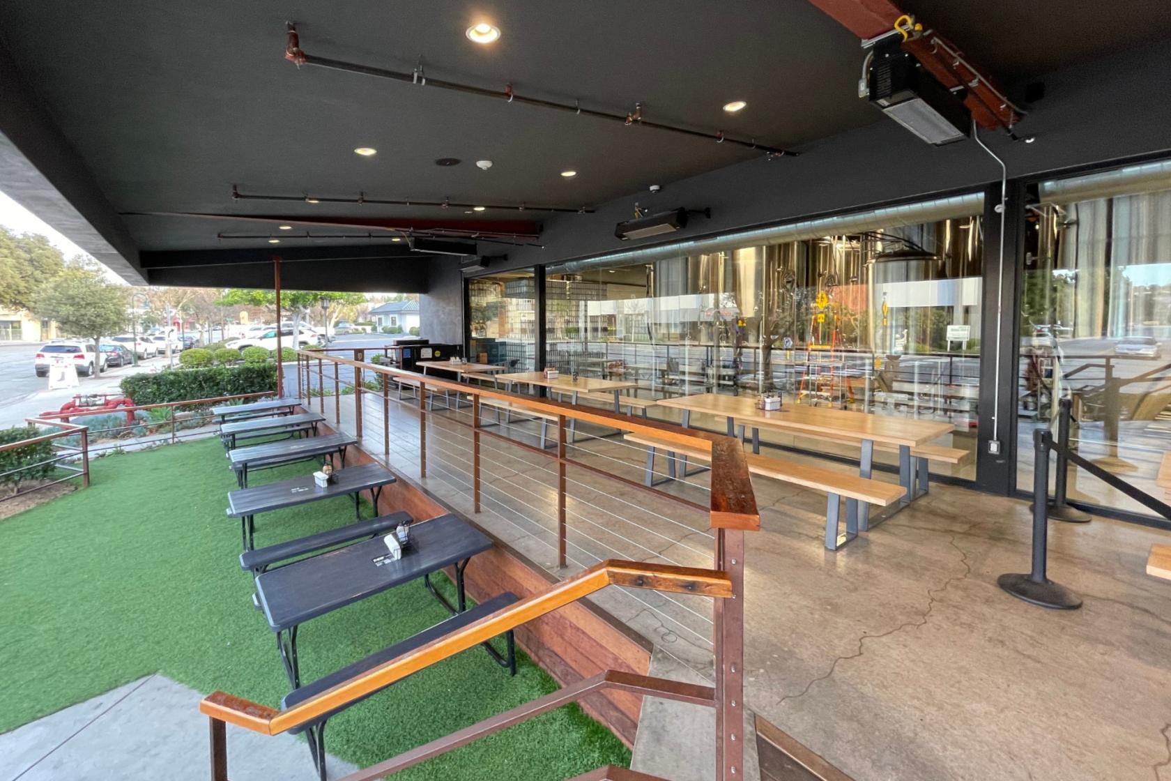 An outdoor space with artificial turf, picnic tables, and a raised patio at Tarantula Hill Brewing Co.