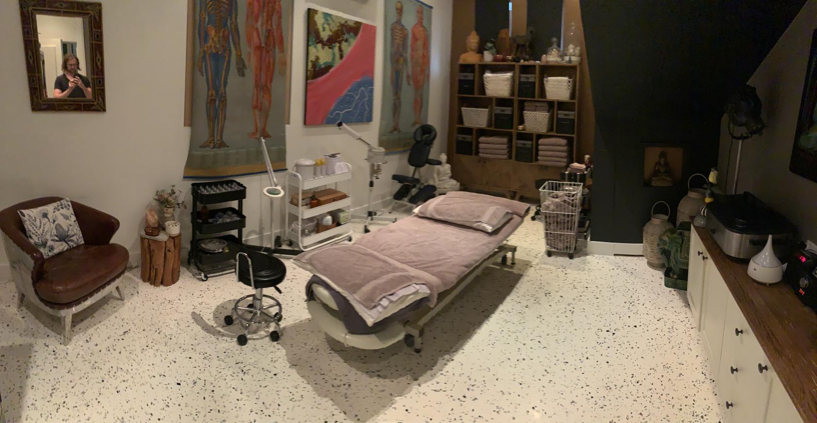 An event venue with a treatment bed, anatomical wall art, medical equipment, and storage baskets at Yogaruka - Drummoyne.