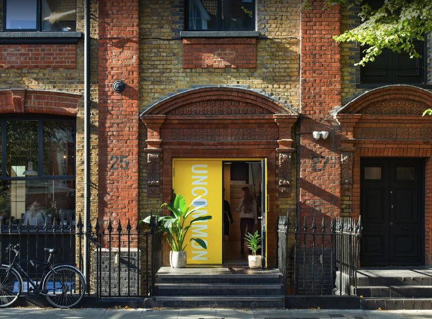 A versatile event space with a red brick facade, yellow entrance, and potted plants at Uncommon Highbury & Islington.