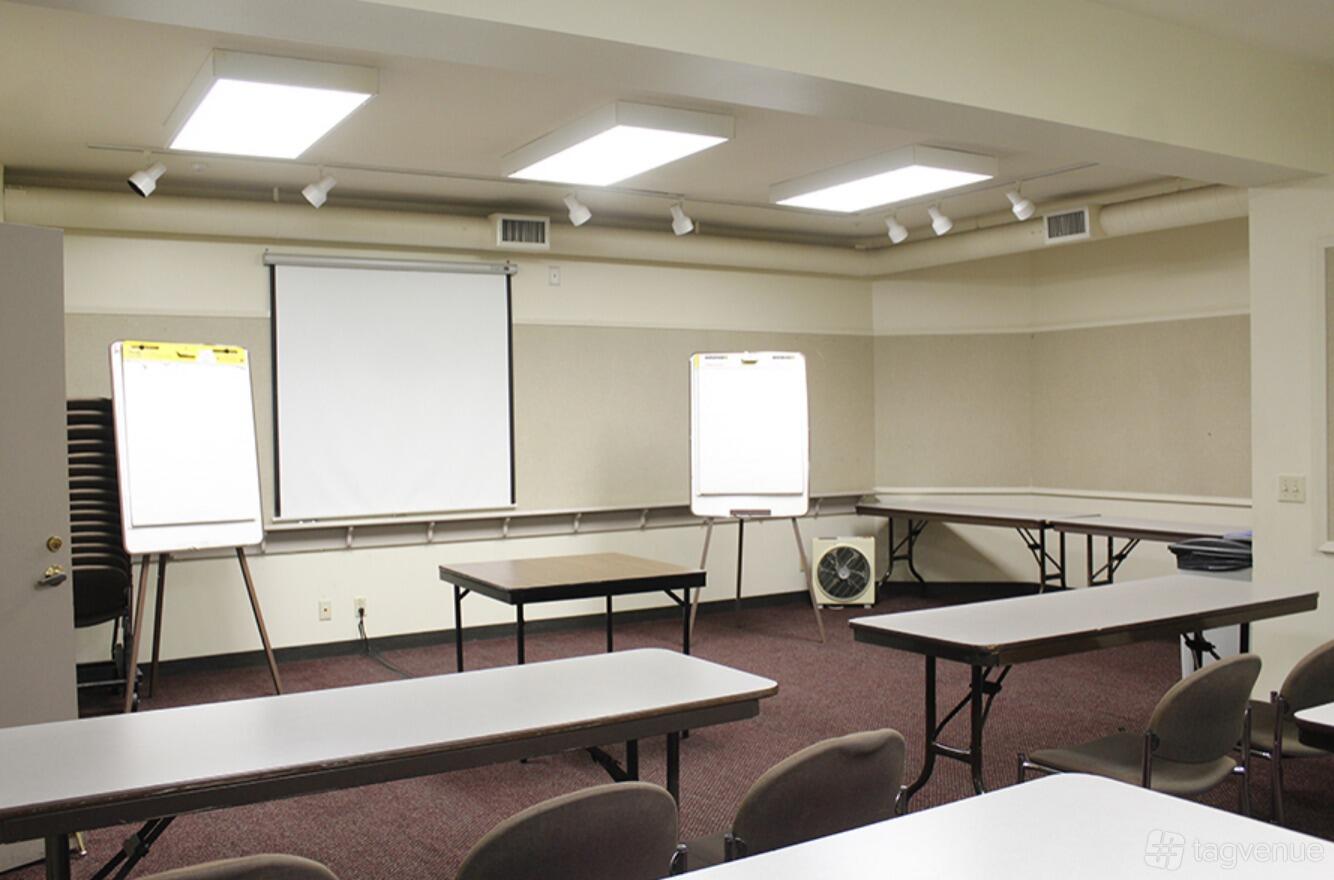An event venue classroom with long tables, a projection screen, and flip charts at Preservation Park.