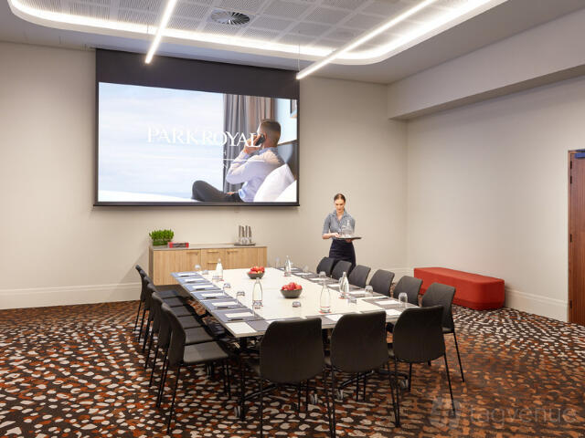 A hotel conference room with a U-shaped table, projector screen, and patterned carpet at PARKROYAL Monash Melbourne.