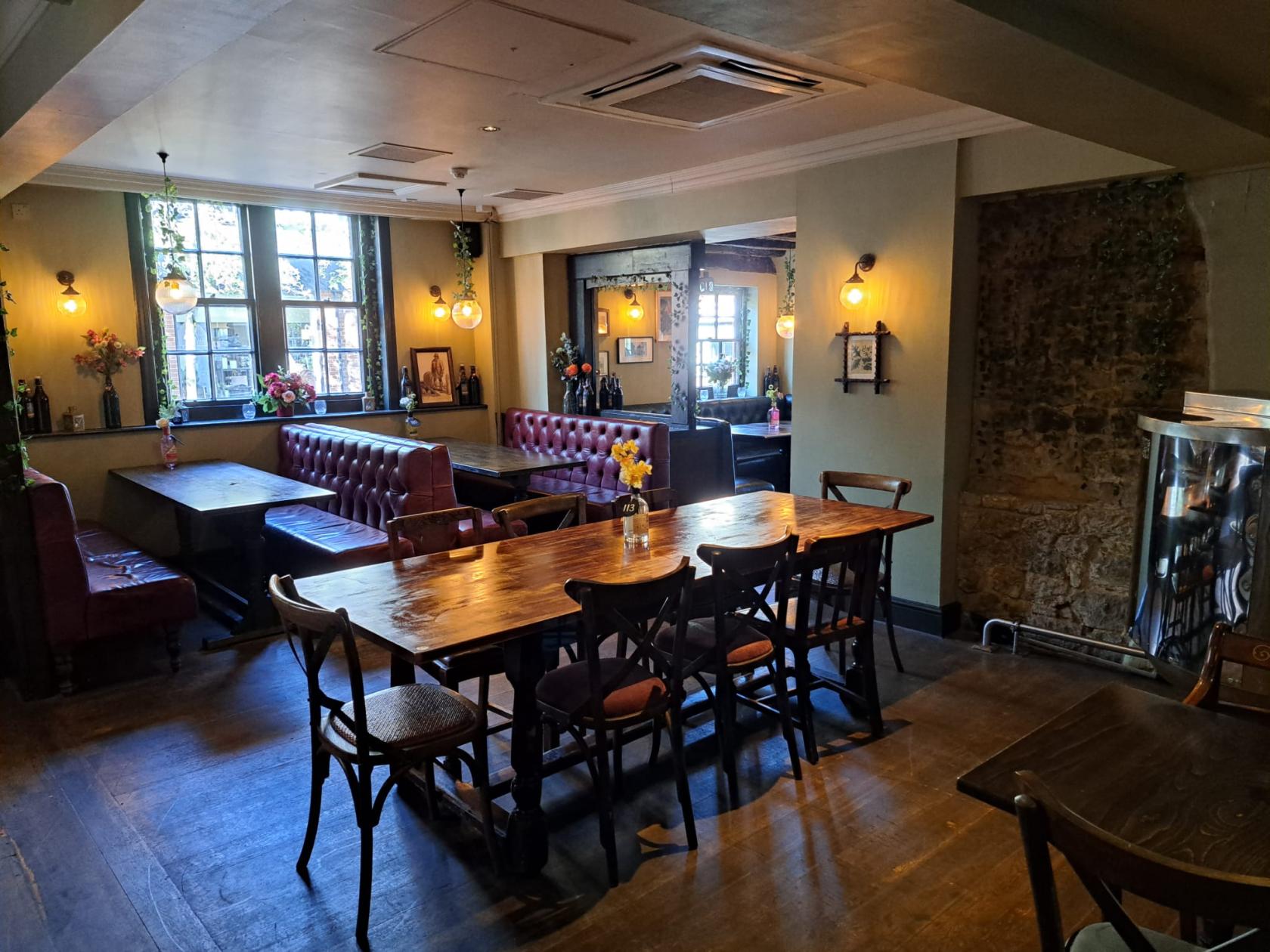 An event space in a restaurant with wood tables, leather banquette seating, and wall sconces at The Oak Tavern.