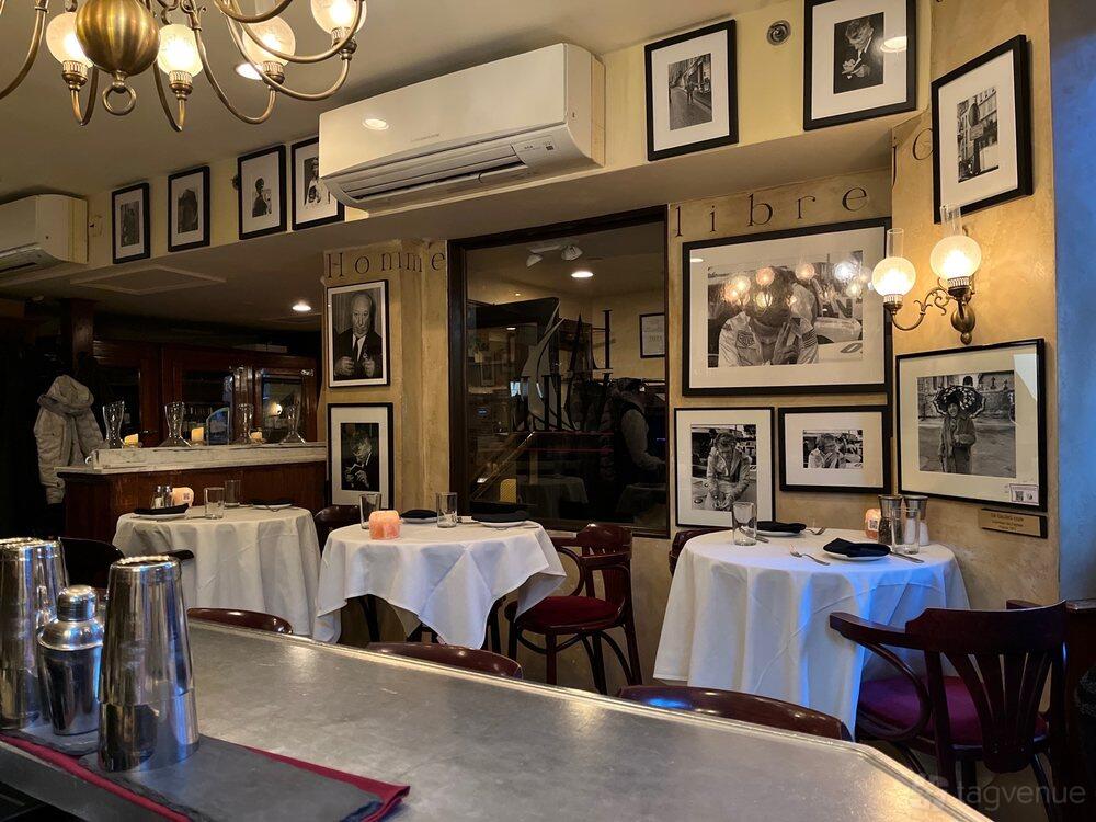 A restaurant with white tablecloths, framed black-and-white photos, and warm wall sconces at La Voile Newbury.