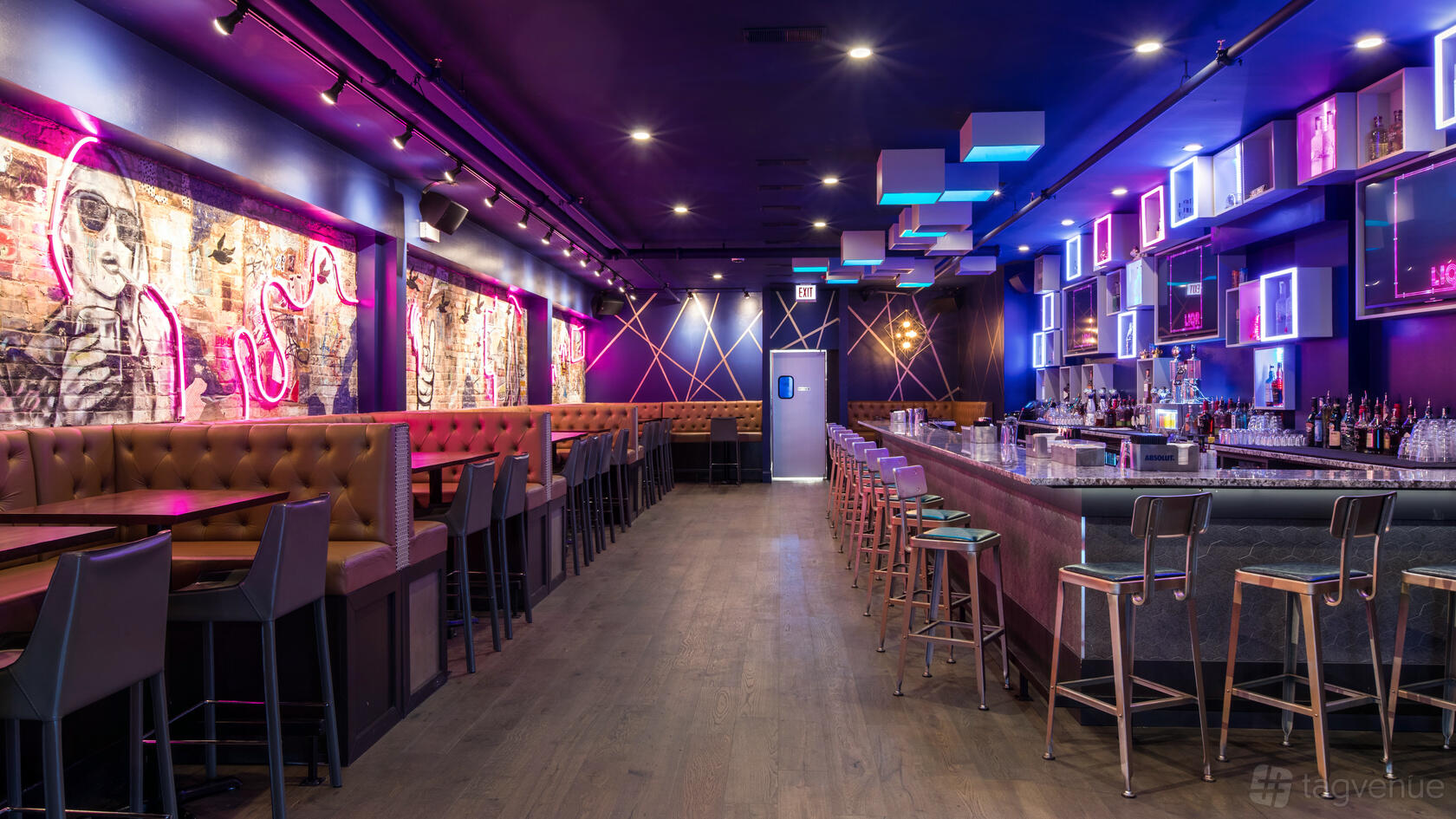 An event space in a nightclub with neon lighting, tufted banquette seating, and a long bar at LiqrBox.