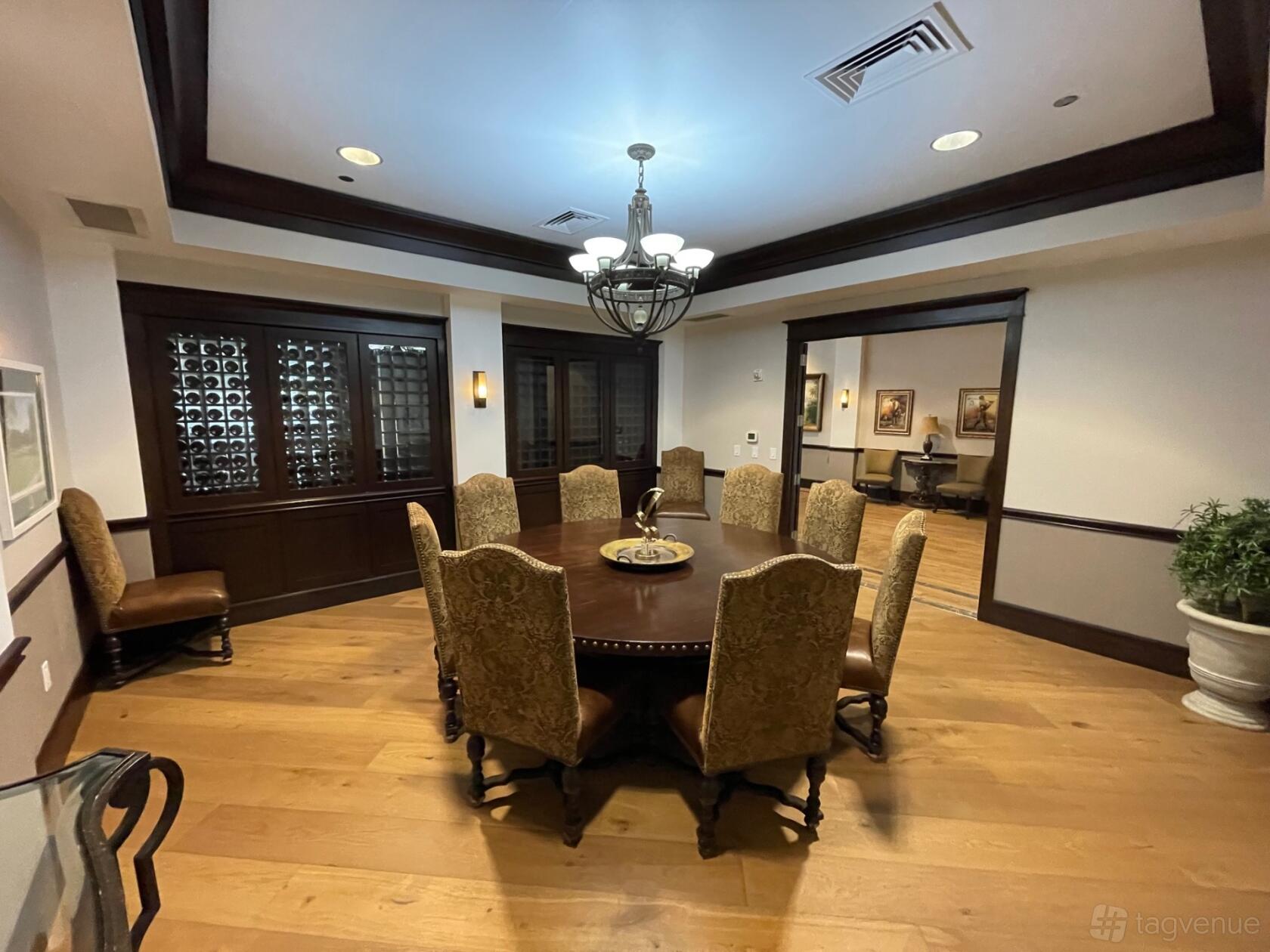 A private dining room with a round table, upholstered chairs, wood flooring, and a wine cabinet at Coyote Ridge Golf Club.