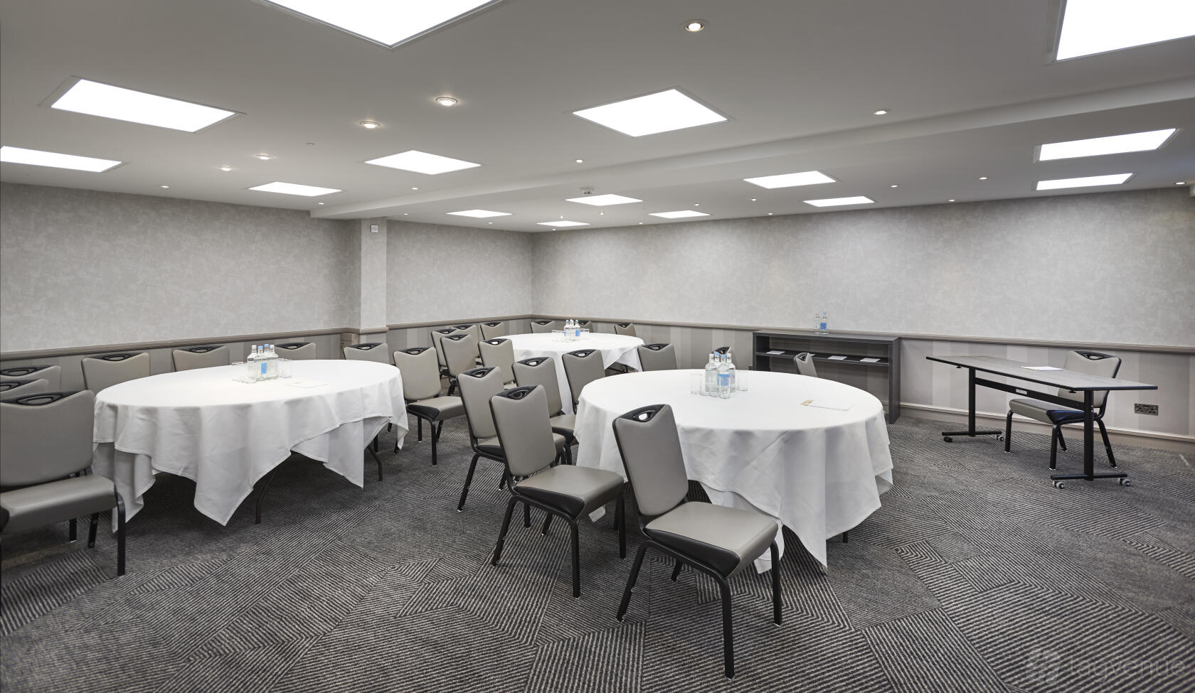 An event space with round tables covered in white linens and upholstered chairs at DoubleTree by Hilton Bristol North.